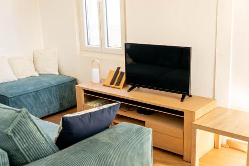 a living room with a flat screen tv on a table at Appartement avec piscine et jacuzzi à 50mètres de la plage et 5min de l'allée des Pins in Argelès-sur-Mer
