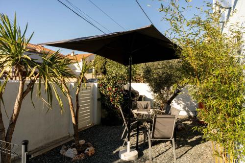 a patio with an umbrella and a table and chairs at Appartement avec piscine et jacuzzi à 50mètres de la plage et 5min de l'allée des Pins in Argelès-sur-Mer
