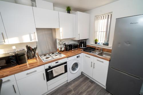 a kitchen with white cabinets and a stainless steel refrigerator at A Swansea Getaway - 3 Bedroom Home with Hot Tub in Swansea