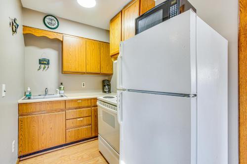 a white refrigerator in a kitchen with wooden cabinets at Michigan Manistee River Cabin about 1 Mi to Downtown in Manistee