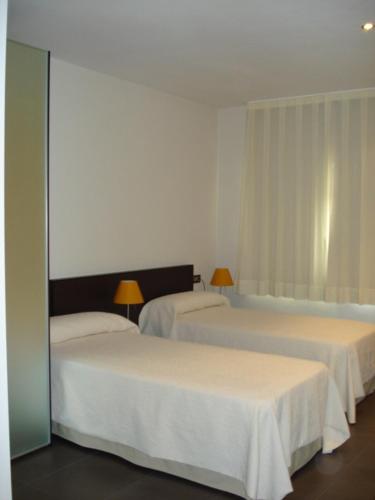 a hotel room with two beds and a window at Archybal Apartamentos Turísticos y Suites in Archena