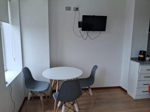 a table and chairs in a room with a tv at Departamento Los Carrera Centro in Osorno