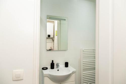 une salle de bain blanche avec un lavabo et un miroir dans l'établissement studio cosy Stade de France 11 pour 2 personnes, à Saint-Denis