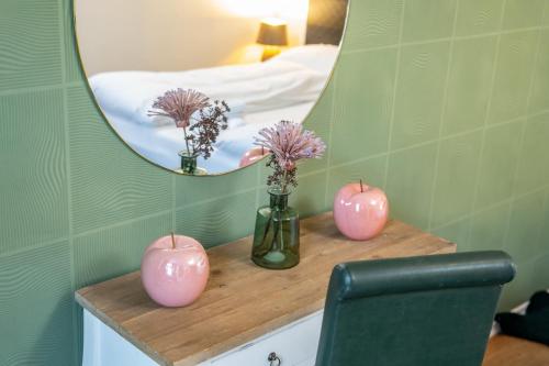 three pink vases on a counter with a mirror at Pension Michelangelo in Eisenach