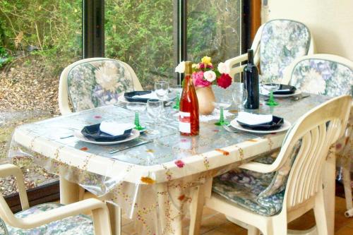 - une table à manger avec des chaises et une table avec une bouteille de vin dans l'établissement Maison charmante à Hourtin avec jardin clôturé, à Hourtin