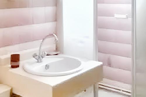 une salle de bain blanche avec un lavabo et un miroir dans l'établissement Maison charmante à Hourtin avec jardin clôturé, à Hourtin