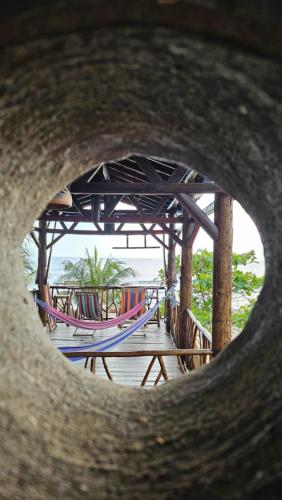 a view of a pier with hammocks through a hole at Mano a Mano Eco Hostal in Las Peñitas