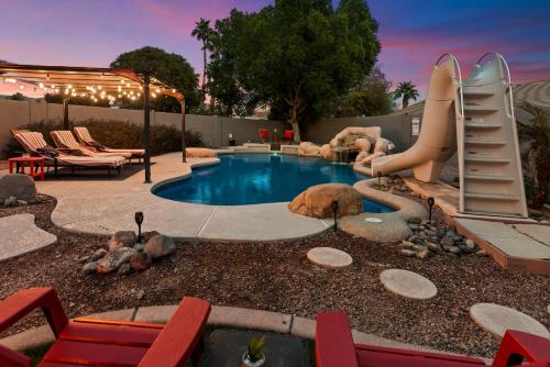 a backyard with a slide and a pool with chairs at 5 Bedroom 4 Bath Boutique Home PREMIUM LOCATION + heated pool option in Glendale