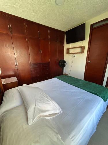 a bedroom with a large white bed with wooden cabinets at Apartamento cerca a aeropuerto in Valledupar