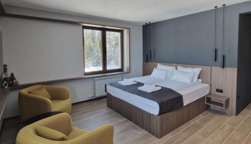 Un dormitorio con una cama y una silla y una ventana. en Nova Planina Jahorina, en Jahorina