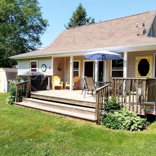 a house with a wooden deck with an umbrella at Little Eden Summer Beach Home in Long Creek