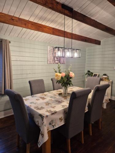 a dining room table with chairs and a vase of flowers at Kozy Kabin in Waterford