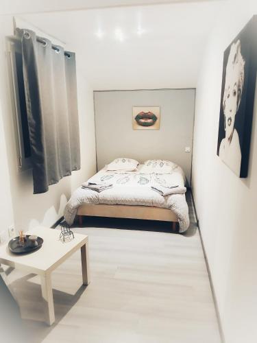 une petite chambre avec un lit et une table dans l'établissement chalonnaise house 120m2, à Châlons-en-Champagne