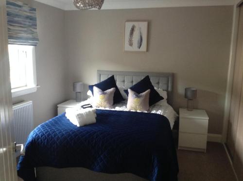 a bedroom with a bed with a blue blanket and pillows at Lovely Riverside Holiday Home in Callander