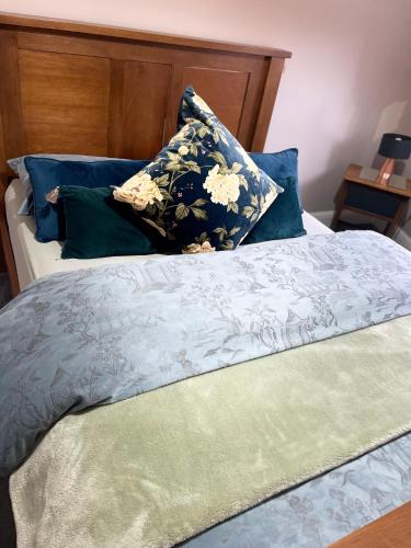 a bed with blue and green pillows on it at Spacious Apartment NEC BHX in Solihull