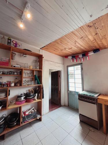 a kitchen with a stove and shelves and a window at SURFHOUSE Pichilemu in Pichilemu