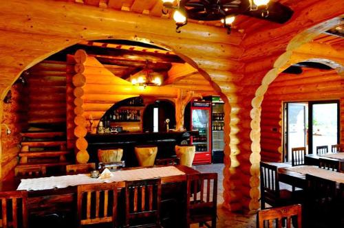 a dining room in a log cabin with tables and chairs at Hanul Prislop in Statiunea Borsa