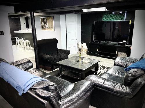 a living room with leather couches and a television at The Price is RIGHT Detroit Home in Detroit