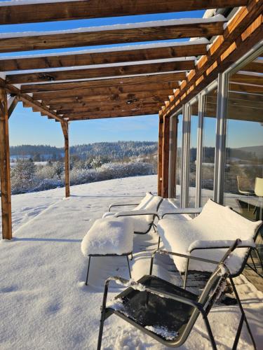 eine Gruppe von Stühlen auf einer schneebedeckten Veranda in der Unterkunft Widokowe Stodoły Bieszczady - domy z panoramą połonin in Lesko