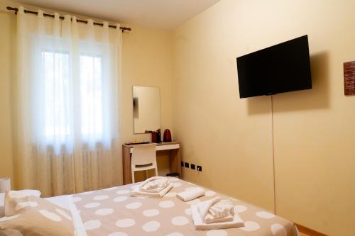 a bedroom with a bed with a television on the wall at CameraCafè in Ferrara