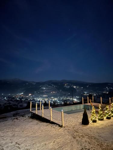 a snow covered slope with christmas trees and a fence at Under Sky Slavske - Котеджі з Теплим басейном ,чаном-джакузі, панорамною ванною та PlayStation 5 in Slavske