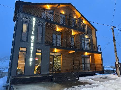 ein hohes Gebäude mit einem Balkon darauf in der Unterkunft Hotel Mountime Kazbegi in Kazbegi