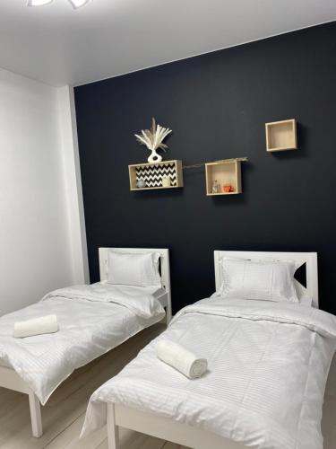two beds in a room with a black wall at Шикарный Гостевой Guest Аpartments MURAGER in Astana