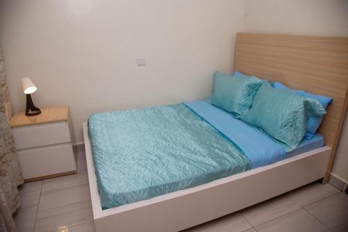 una camera da letto con un letto con lenzuola blu e una lampada di La Perle de Ville a Kigali