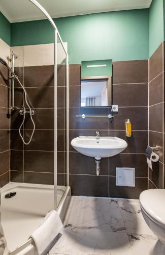 a bathroom with a sink and a shower and a toilet at Pension Michelangelo in Eisenach