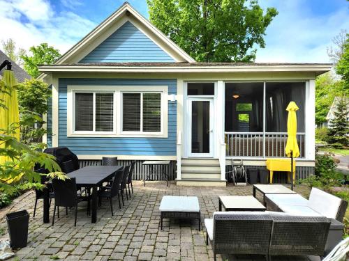 una casa blu con patio arredato con tavoli e sedie di L'Hibou - 18 Farm View a Cherry Valley