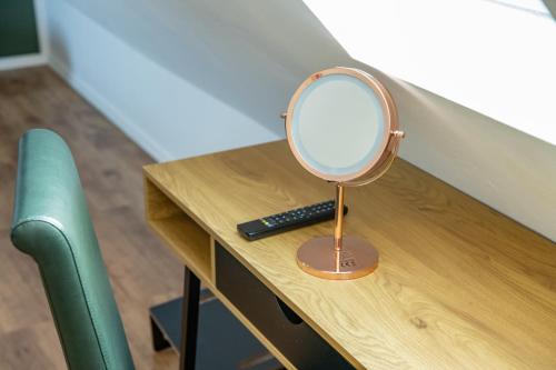 a mirror on a wooden desk with a remote control at Pension Michelangelo in Eisenach
