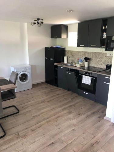 a kitchen with black cabinets and a wooden floor at Sun&Fun Vendégház in Balatonakarattya