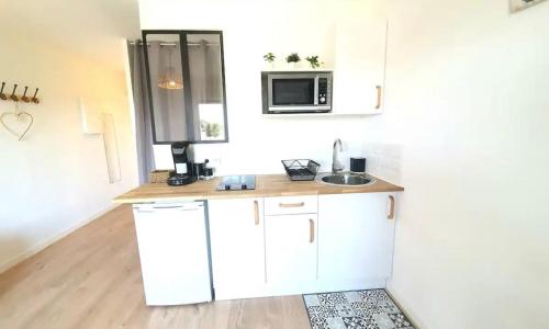 une cuisine avec des armoires blanches et un évier dans l'établissement Appartement à 500m de la plage, à Canet
