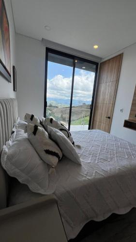 a bedroom with a large bed with a large window at Montecielo Hosting in Guatapé