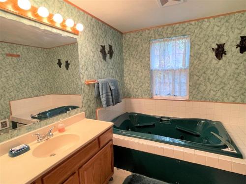 a bathroom with a green tub and a sink at Mossy Moose Cabin | Near White Pass & Mt Rainier in Packwood