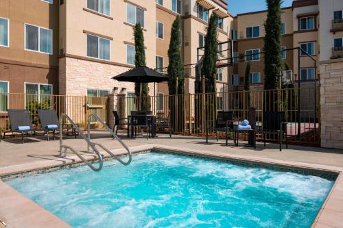a large swimming pool with chairs and an umbrella at Residence Inn by Marriott Redwood City San Carlos in San Carlos