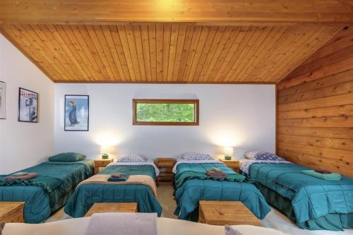 a room with four green beds and a wooden ceiling at Trails End | Hot Tub, Starlink, Woodstove in Packwood