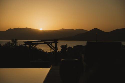 a sunset over a body of water with a table at Villa Morby in Paleros