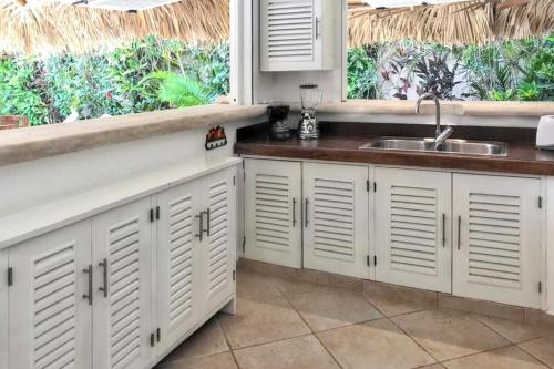 Una cocina con gabinetes blancos y un fregadero y una ventana. en Charming house with private pool in Las Terrenas, en Las Terrenas