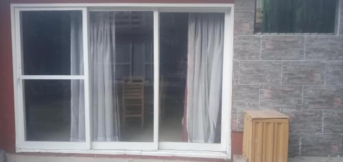 a window with white curtains next to a brick wall at Inti Mayu in Villa Cura Brochero