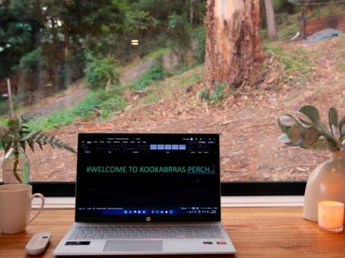 a laptop computer sitting on a desk next to a window at Kookaburra's Perch in Millgrove