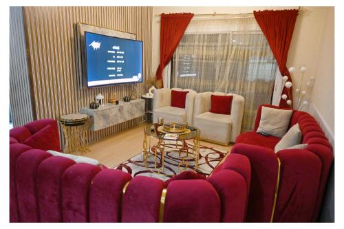 a living room with red chairs and a large screen at Ajman Pearl Tawer Block B4-807 in Ajman