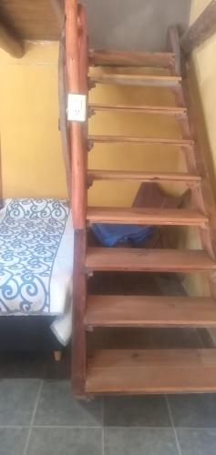 a set of wooden stairs next to a bed at Inti Mayu in Villa Cura Brochero