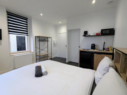 a bedroom with a large white bed and a kitchen at Le coin des rêves in Roanne