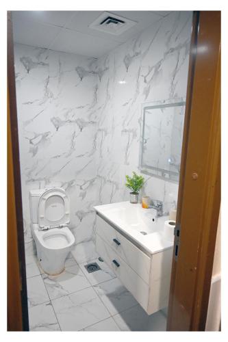 a white bathroom with a toilet and a sink at Ajman Pearl Tawer Block B4-807 in Ajman