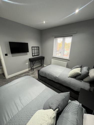 a bedroom with two beds and a flat screen tv at Galway Glamour in Bircotes