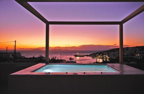 a swimming pool with a sunset in the background at Agave Donousa Suites in Donoussa