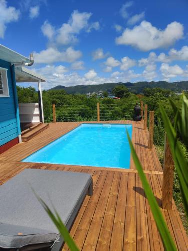 a swimming pool on a wooden deck next to a house at Lodge Eden Caraibes 6p avec piscine privée 6x3 in Sainte-Anne