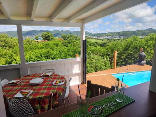 a porch with a table and a view of a pool at Lodge Eden Caraibes 6p avec piscine privée 6x3 in Sainte-Anne