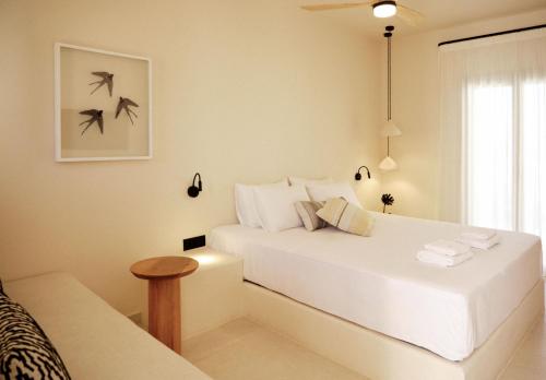 a white bedroom with a bed and a window at Agave Donousa Suites in Donoussa